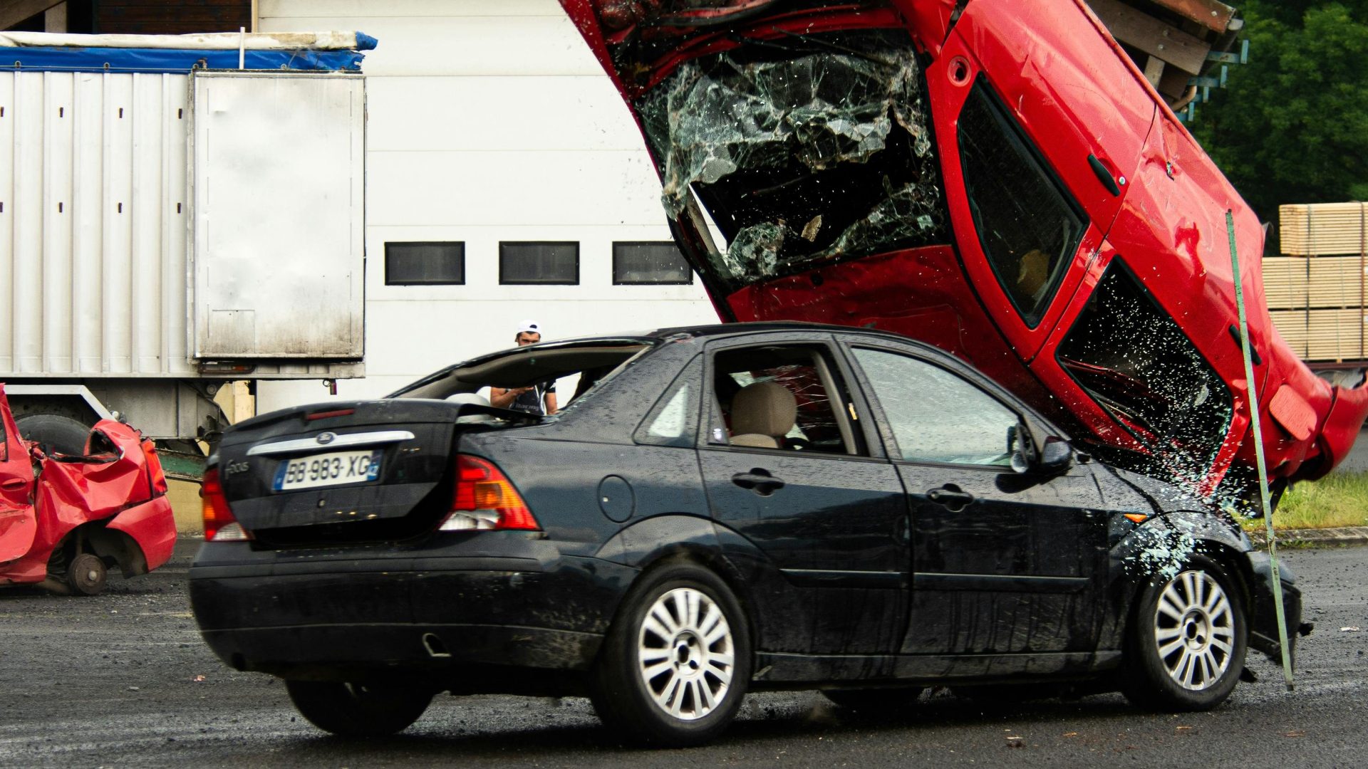 Ein spektakulärer Auto-Stuntunfall, bei dem ein rotes Auto im Freien auf ein schwarzes Fahrzeug kippte.